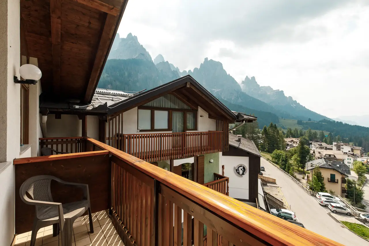 Dal balcone di legno dell'albergo, oltre il tetto della casa di fronte, le Pale di San Martino nella foschia
