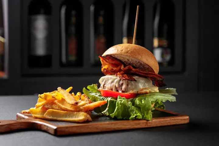 L'hamburger gourmet con patate e insalata sul tagliere di legno