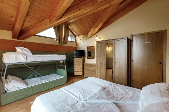 Camera quadrupla dell'Hotel Montanara sotto il tetto di legno: letto a castello e letto matrimoniale
