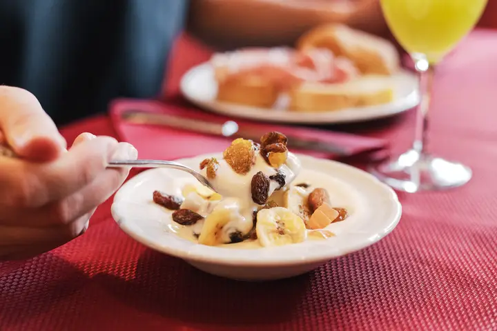 Una coppa di yogurt con frutta secca e banana sulla tovaglia rossa